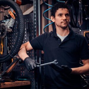 young attractive mechanic is posing bicycle his own workshop